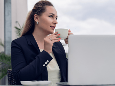 Kobieta siedząca przy stole z kubkiem herbaty, zastanawiająca się nad ważnym wyborem.