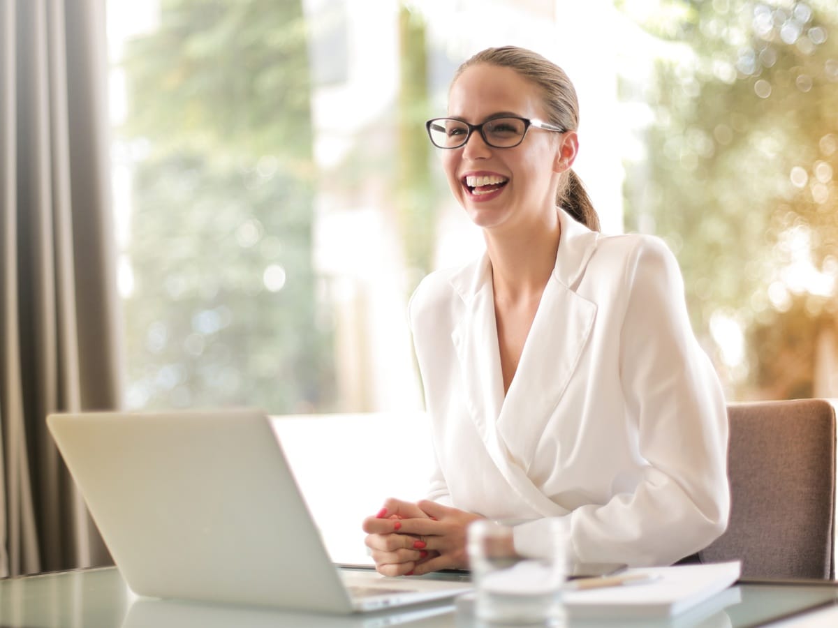 Mentorka finansowa pracuje przy laptopie i uśmiecha się