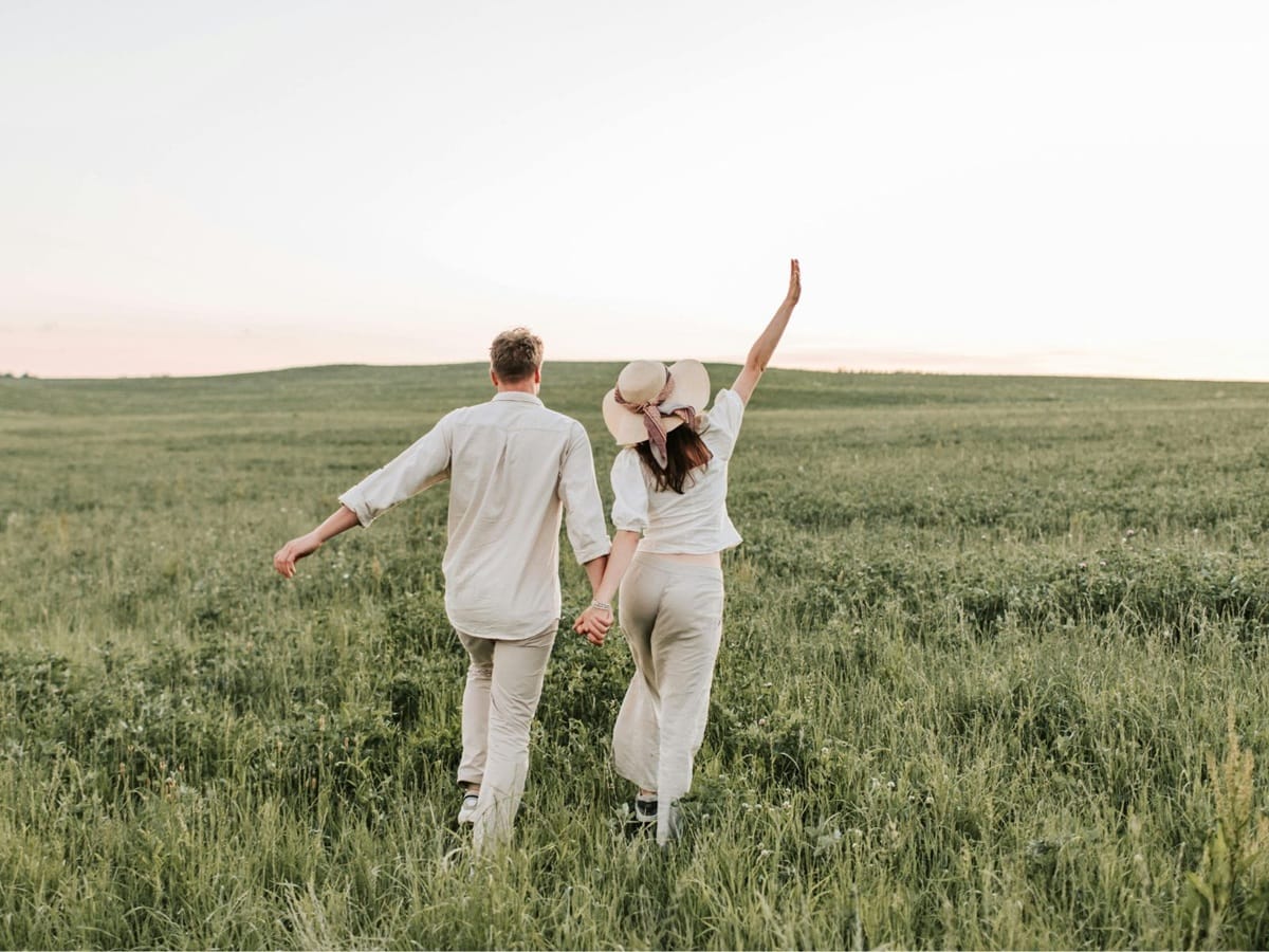 Para 30+ idąca razem po trawie, widziana od tyłu,  symbol wspólnej drogi i trwałego związku.