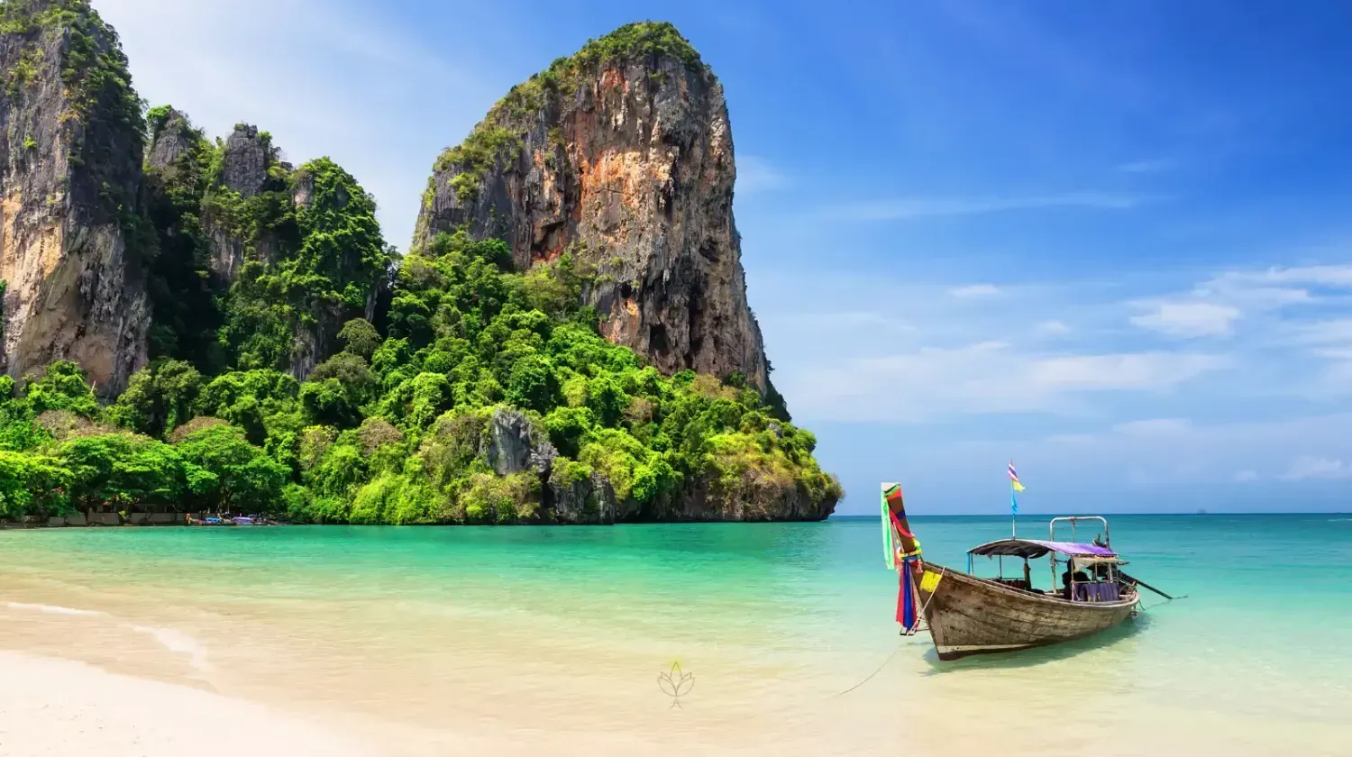 Traditional long-tail boat on a tropical Thai beach with limestone cliffs and turquoise water in Krabi.