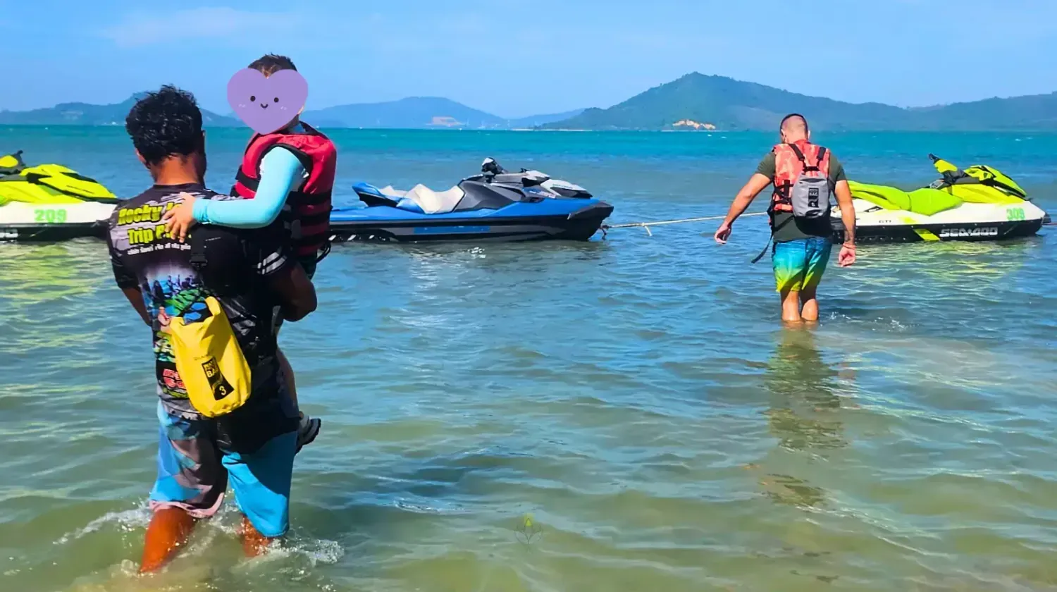 Expat child with life jacket helped by locals on a jet ski adventure in Thailand, showing fun family activities.