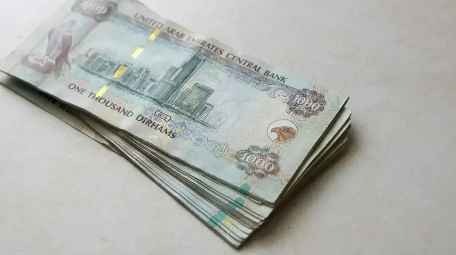 Stack of 1000 UAE dirham banknotes – representing Dubai corporate tax, business banking setup, and financial regulations.