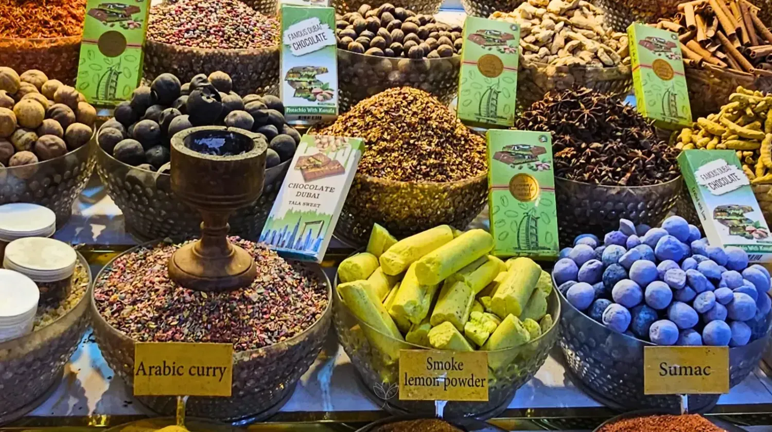 Colorful spice market in Dubai with Arabic spices and chocolates – symbolizing hidden fees and broker traps when starting a company.