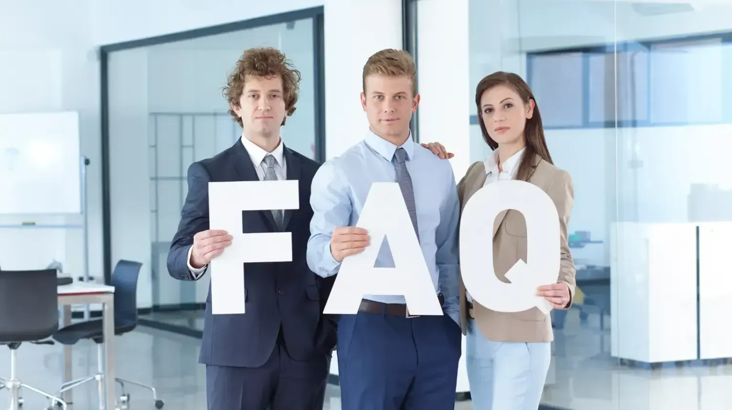 Business team holding large FAQ letters — frequently asked questions about buying property in Dubai for expats and first-time investors.