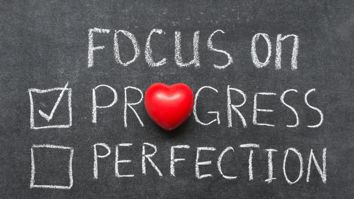 Chalkboard message saying “Focus on progress, not perfection” with a red heart symbol.