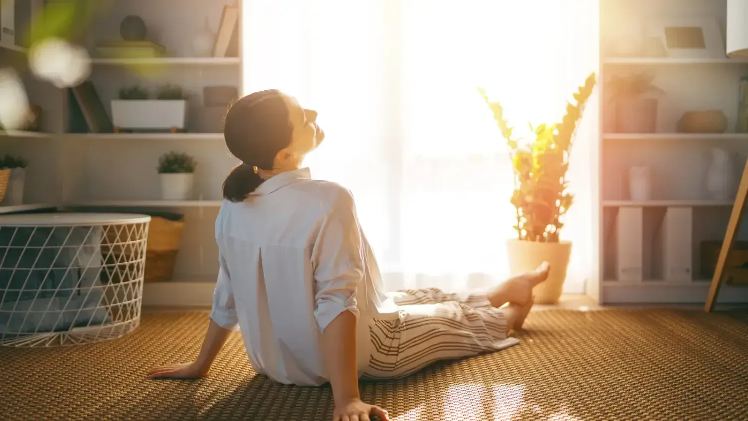 Woman relaxing on the floor in warm sunlight, symbolizing rest, recovery, and avoiding burnout on the business journey.