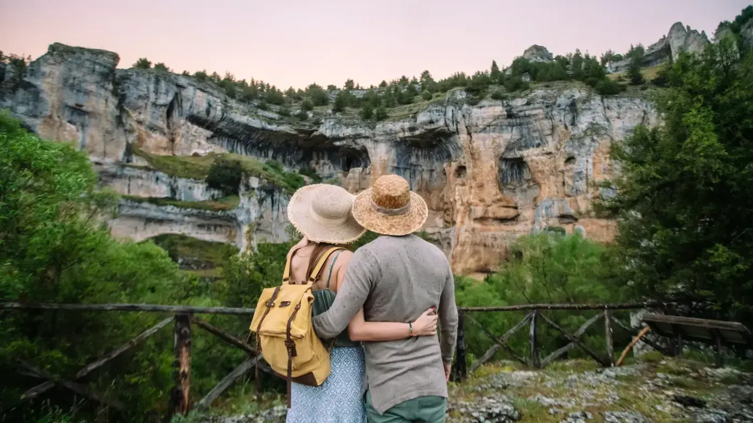 Couple hugging while looking at scenic rocky cliffs during a nature trip at sunset