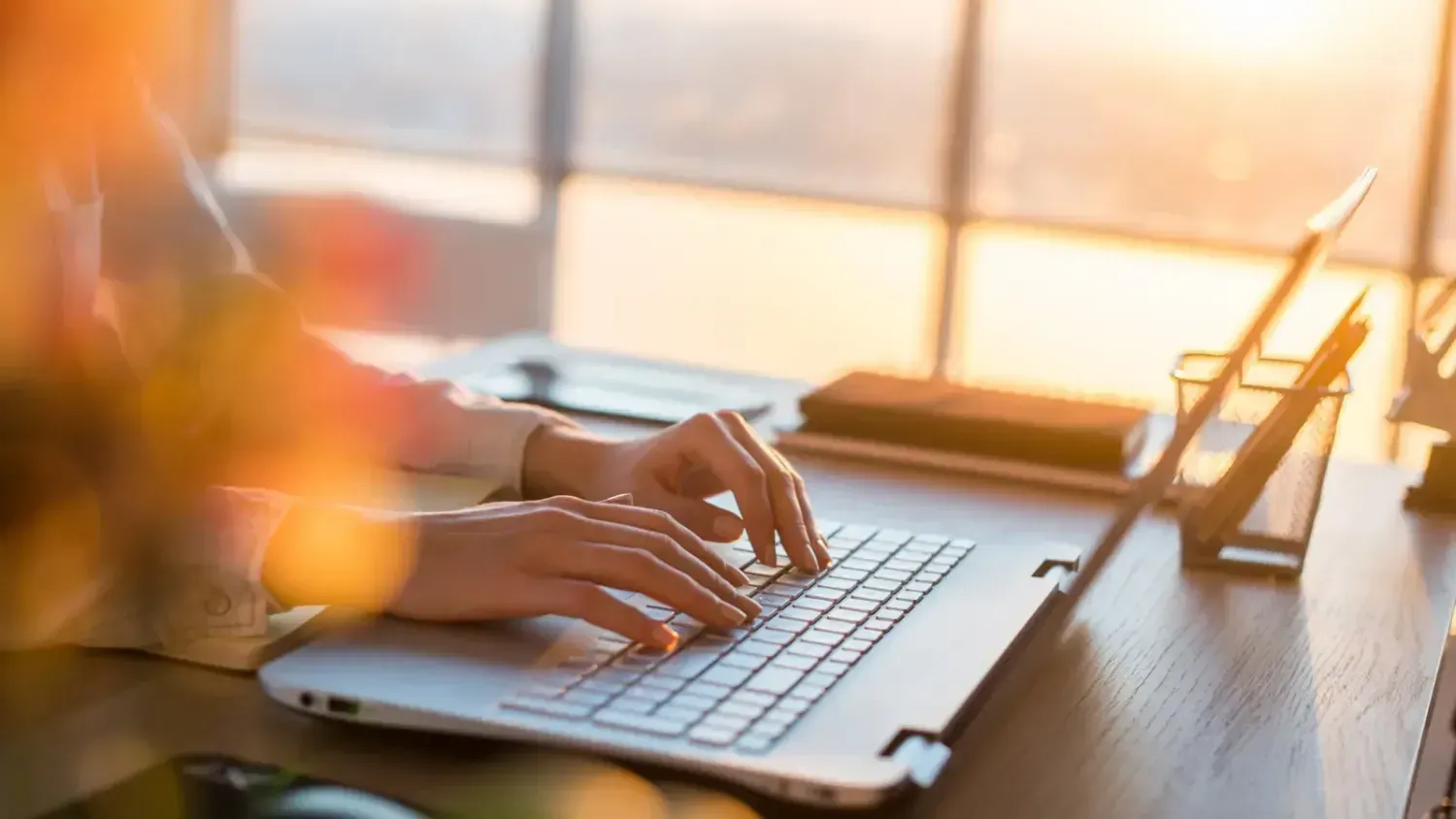 Person typing on a laptop at sunset while creating digital content