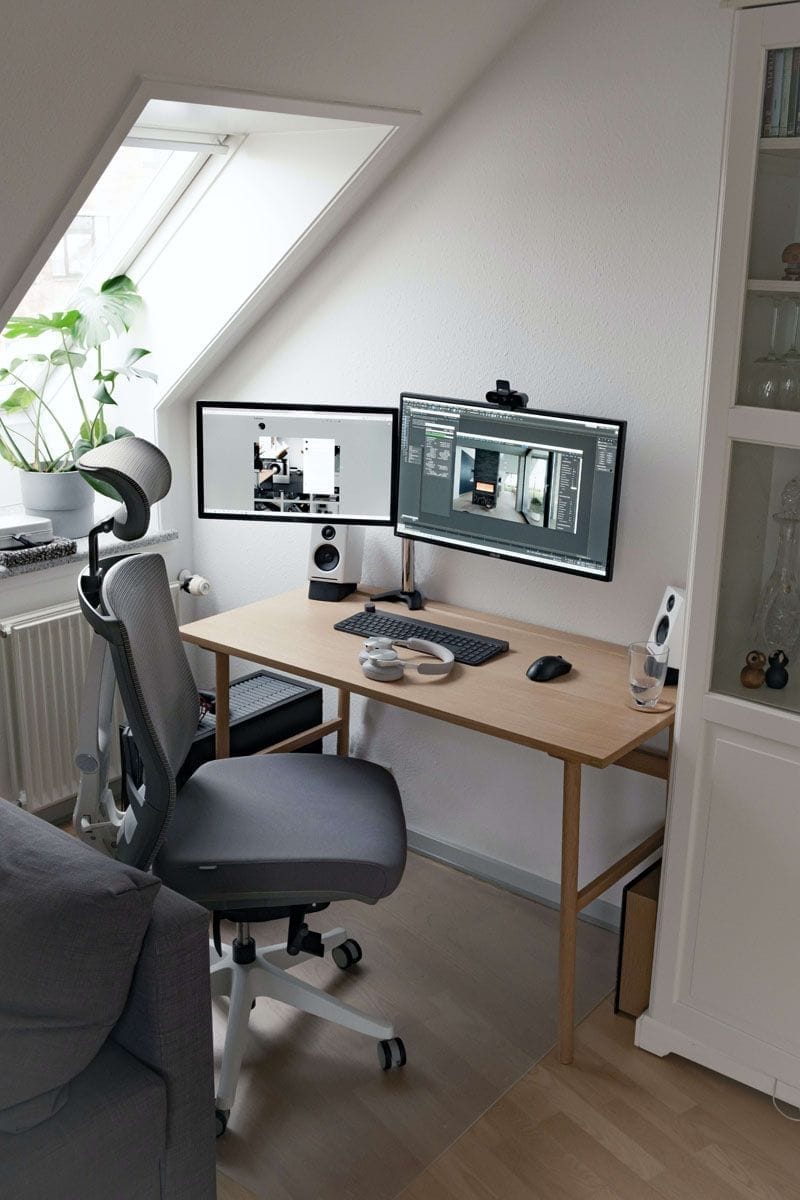 Office desk and chair setup with computer screens on the desk	