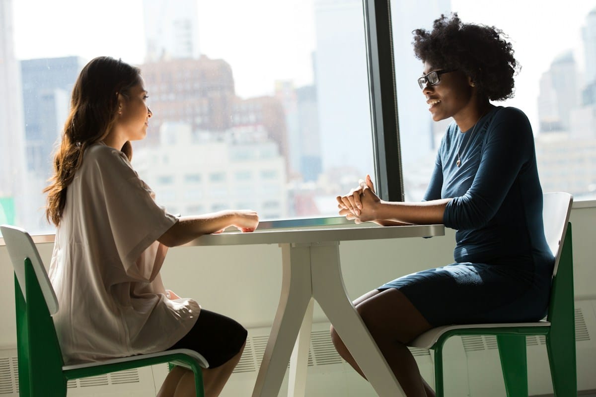 Deux femmes en conversation dans un cadre lumineux et professionnel.
