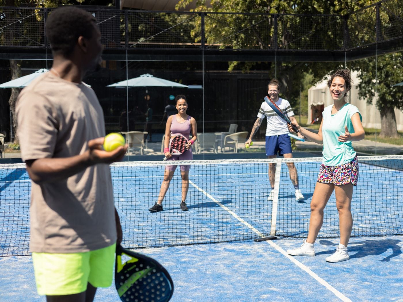 Players laughing during a game of padel on a sunny court