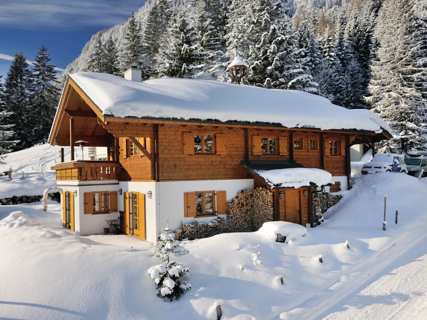 A wooden chalet in the snow in front of a pine forest