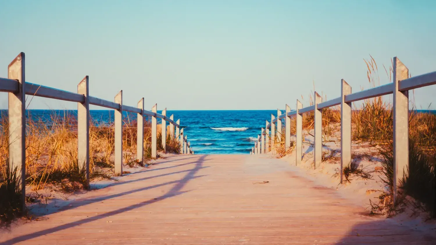 Sandy boardwalk leading to ocean view – symbolizing realignment, clarity, and a new version of success through burnout recovery.
