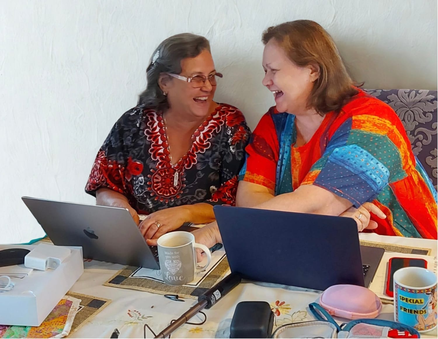 Quirky Quilt Art sisters laughing and collaborating on a quilting and fabric art project, enjoying creativity and teamwork in the studio.
