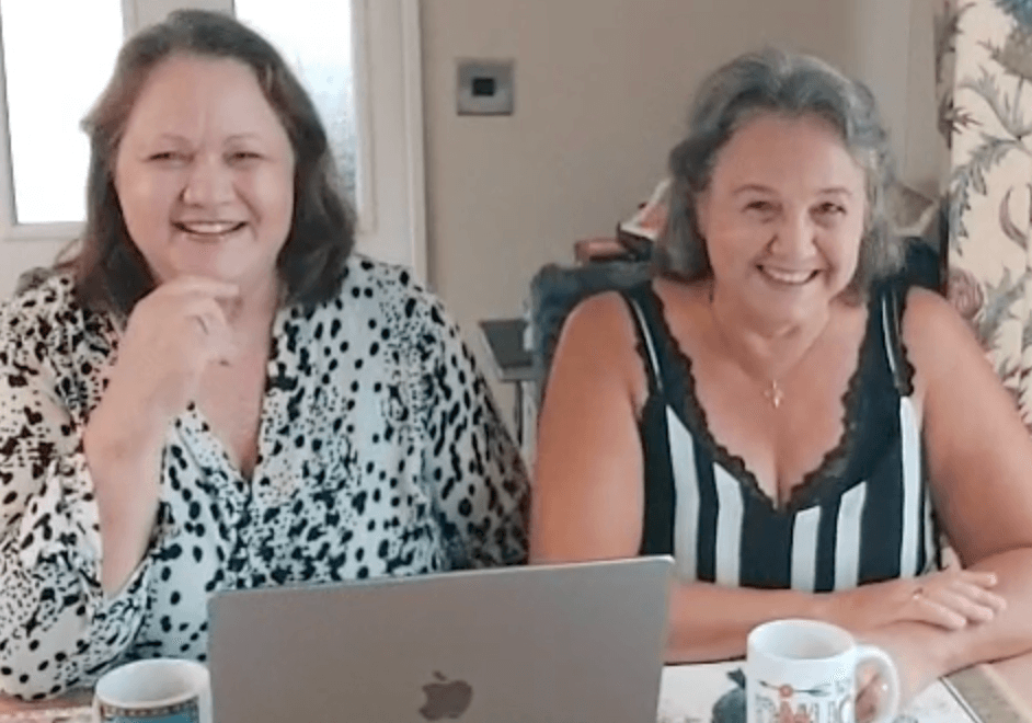 Elaine and Marlene of Quirky Quilt Art smiling at their studio desk, welcoming messages from quilters and creatives