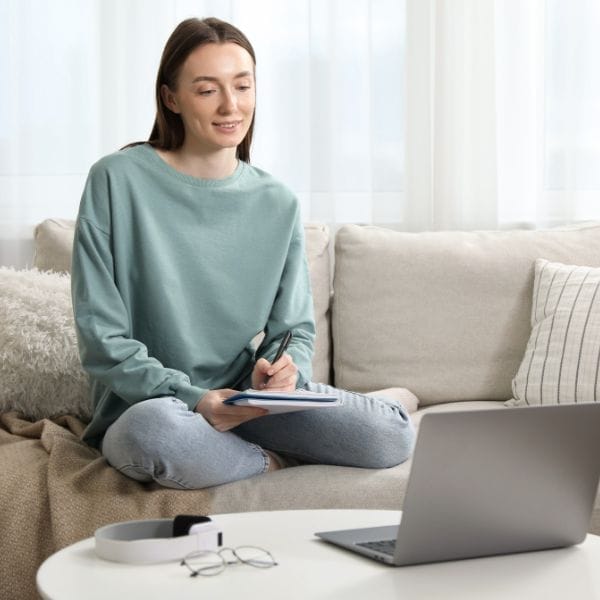 Mujer trabajando con cuaderno y portátil para ganar claridad sobre lo que le ocurre emocionalmente