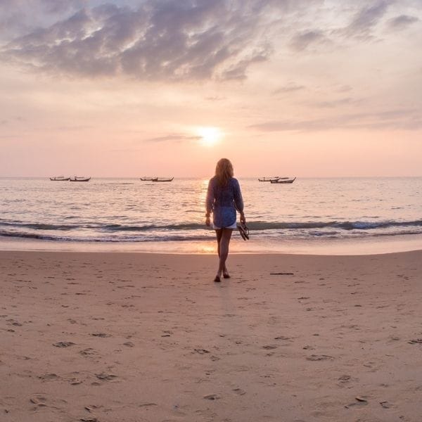 Mujer caminando hacia el mar al atardecer representando calma y regulación emocional