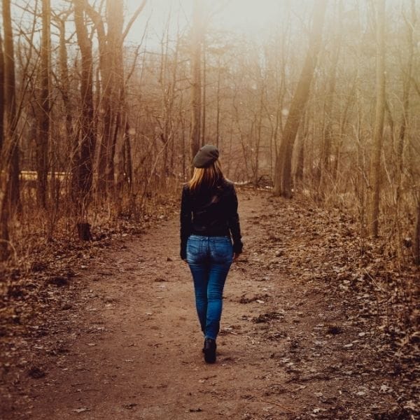 Mujer caminando sola por el bosque en un momento de ansiedad y búsqueda de calma interior