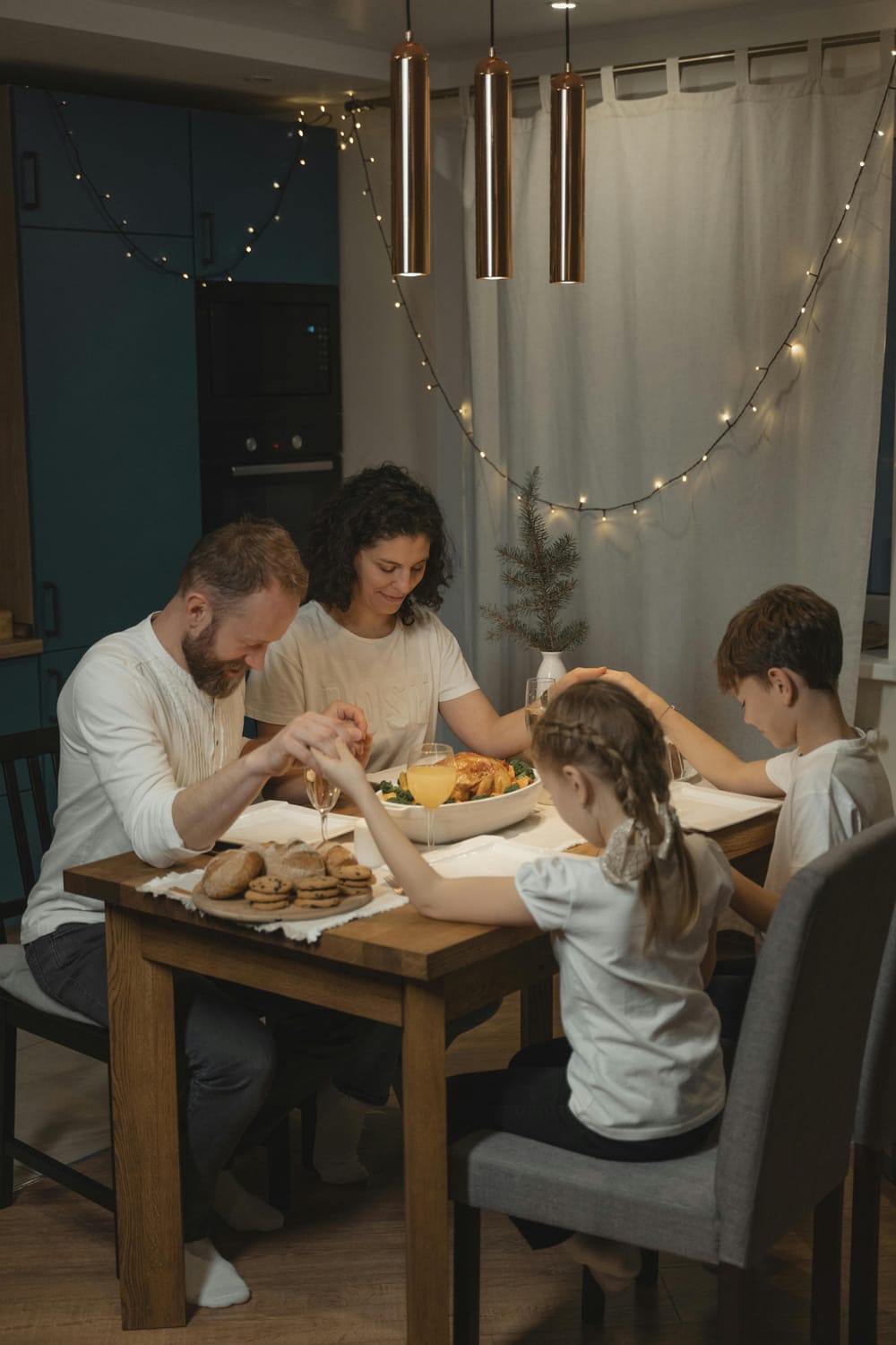 Family sitting a dinner table saying a prayer