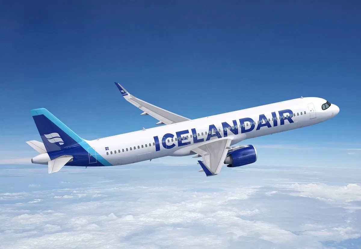 Icelandair airplane flying against blue skies with white clouds, offering direct flight options from the United States to Iceland.