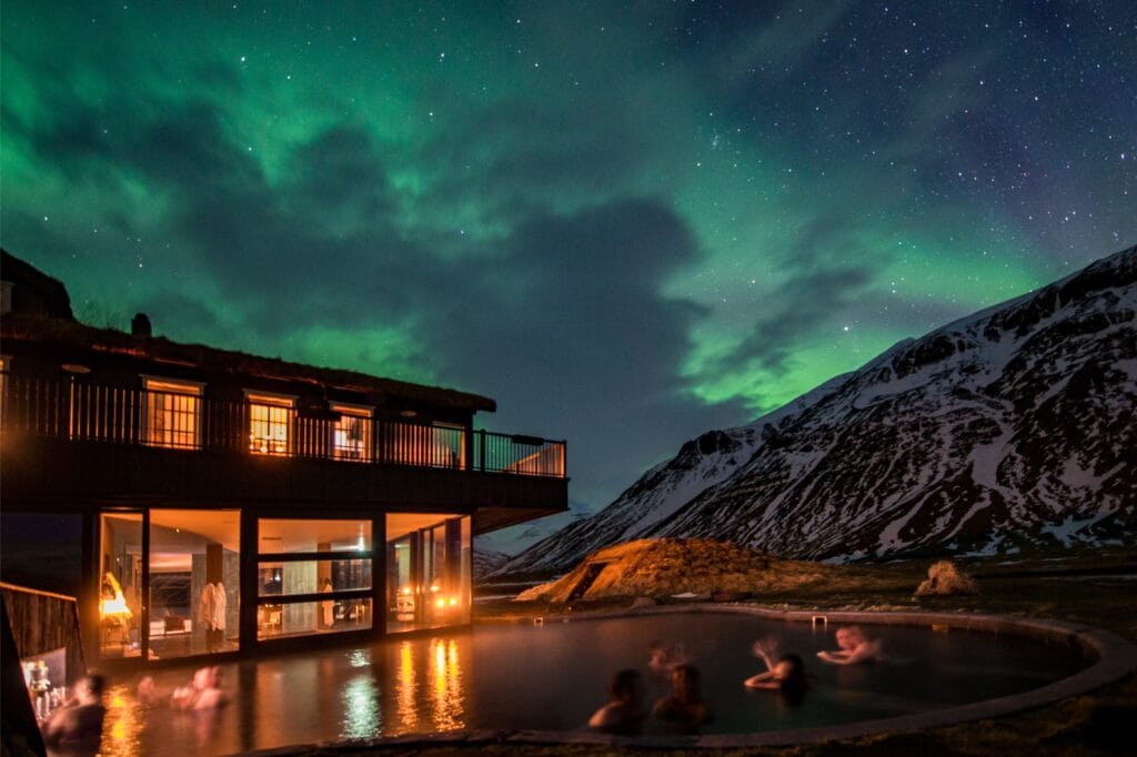 Luxury hotel in Iceland with outdoor geothermal pool beneath the northern lights, located near prime viewing areas for the Iceland total solar eclipse.
