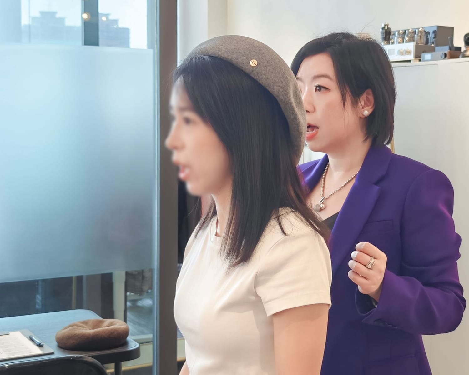 學員戴上帽子後與導師檢視鏡中效果