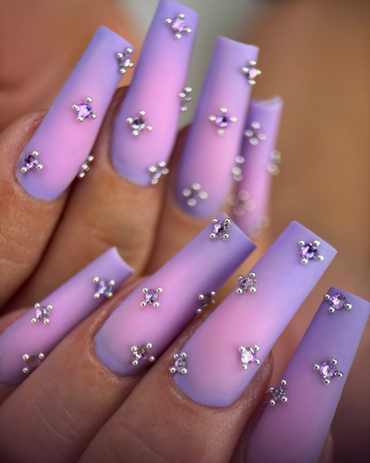 Pose d’ongles longs violets avec décorations incrustées