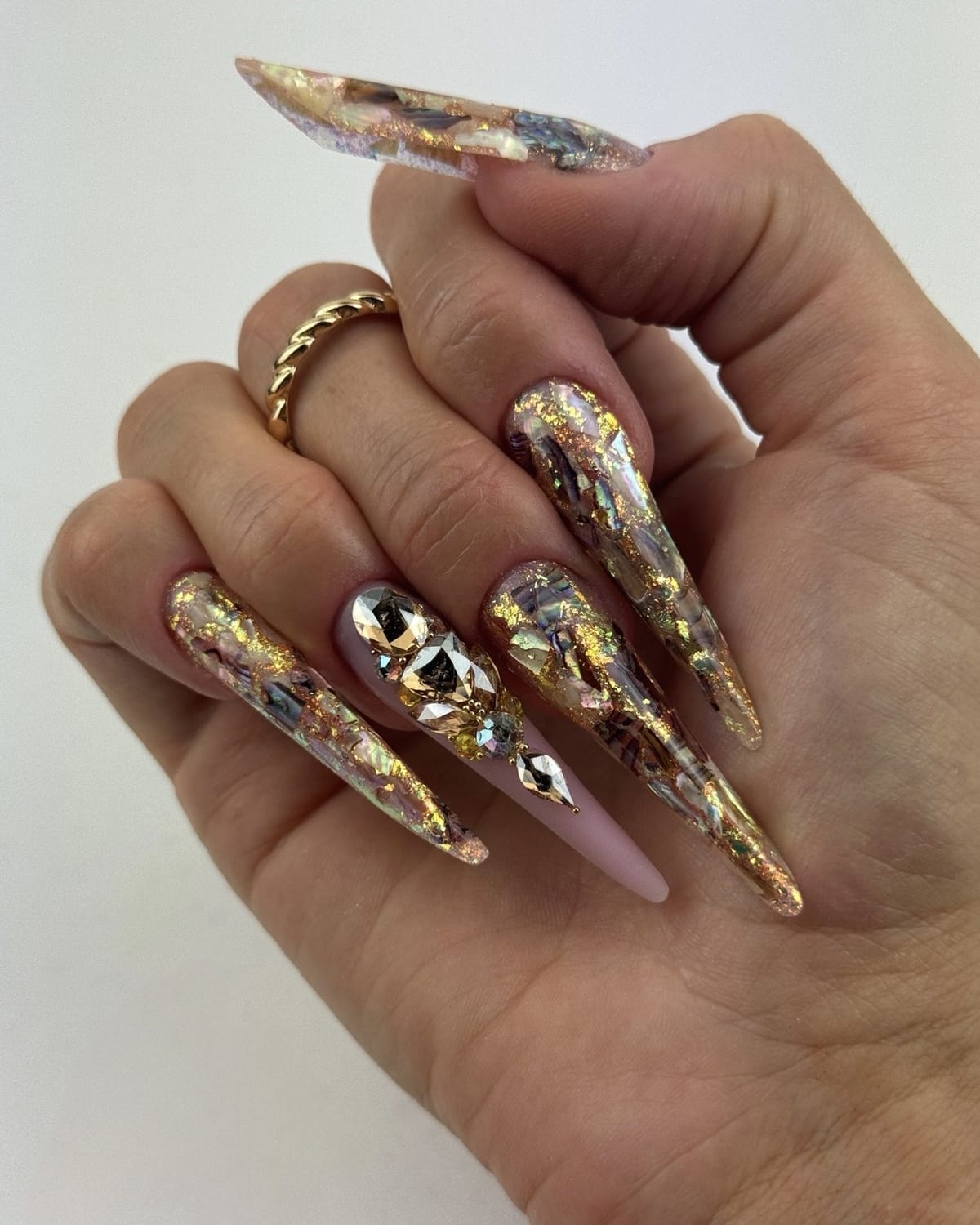 Pose d’ongles longs artistiques avec incrustations et effets de matière