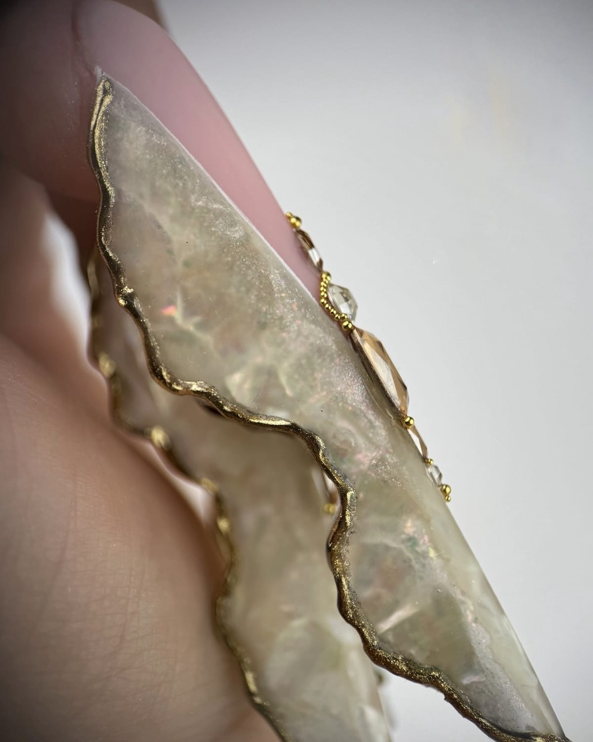 Détail d’un ongle artistique sculpté avec travail de matière et contours dorés