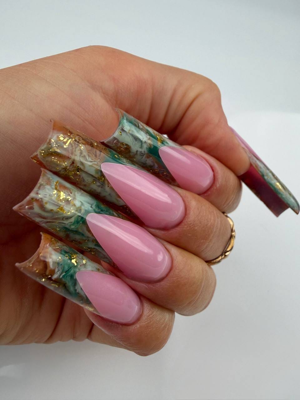Pose d’ongles rose brillante en forme amande avec extensions artistiques marbrées vertes et dorées