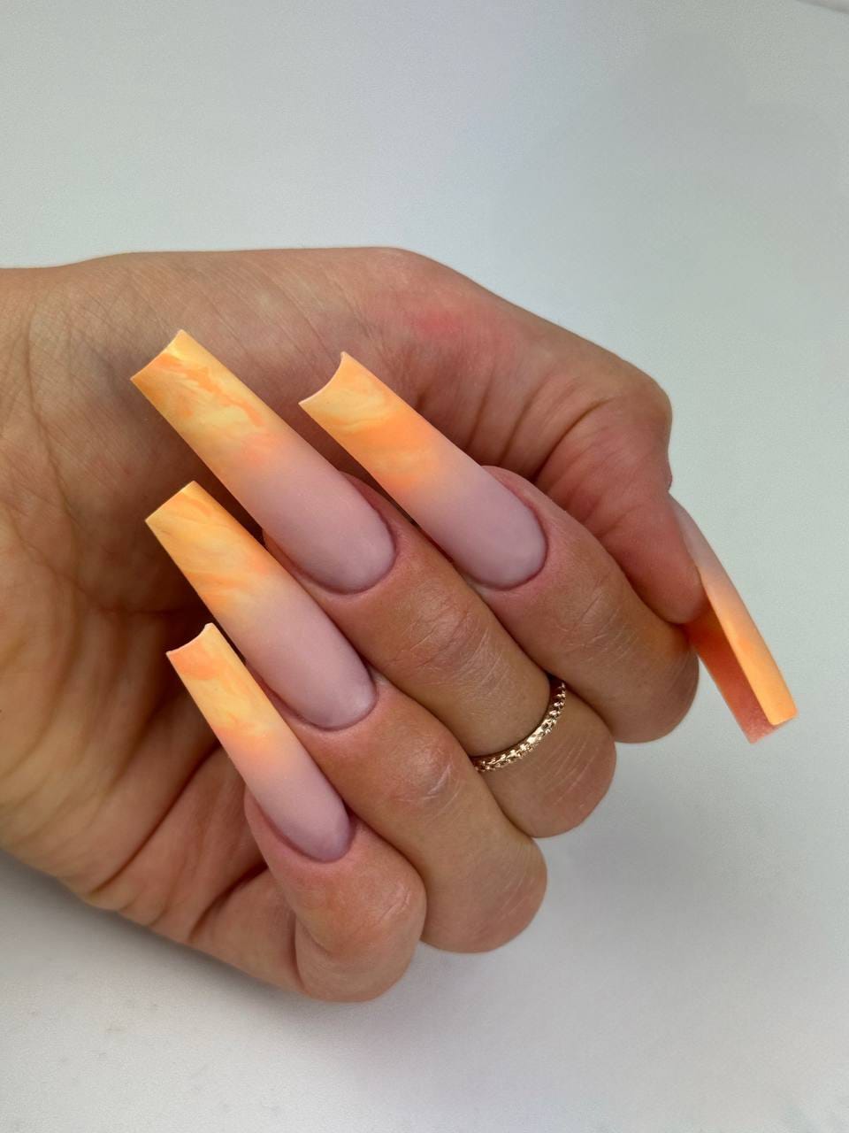 Pose d’ongles longs carrés avec dégradé nude et effet marbré orange lumineux