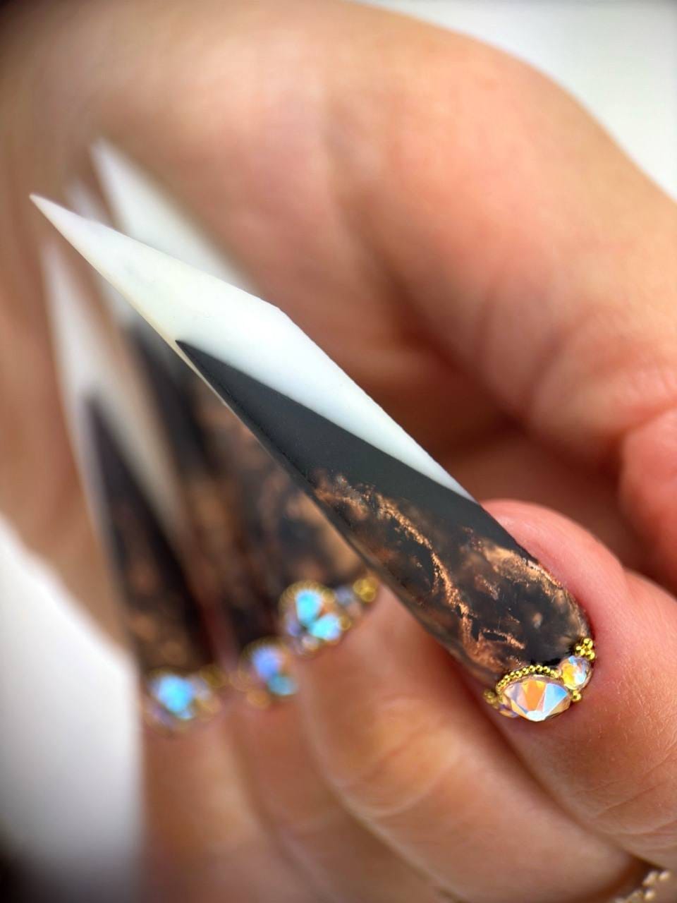 Pose artistique stiletto noire blanche et cuivrée avec bijoux d’ongles brillants