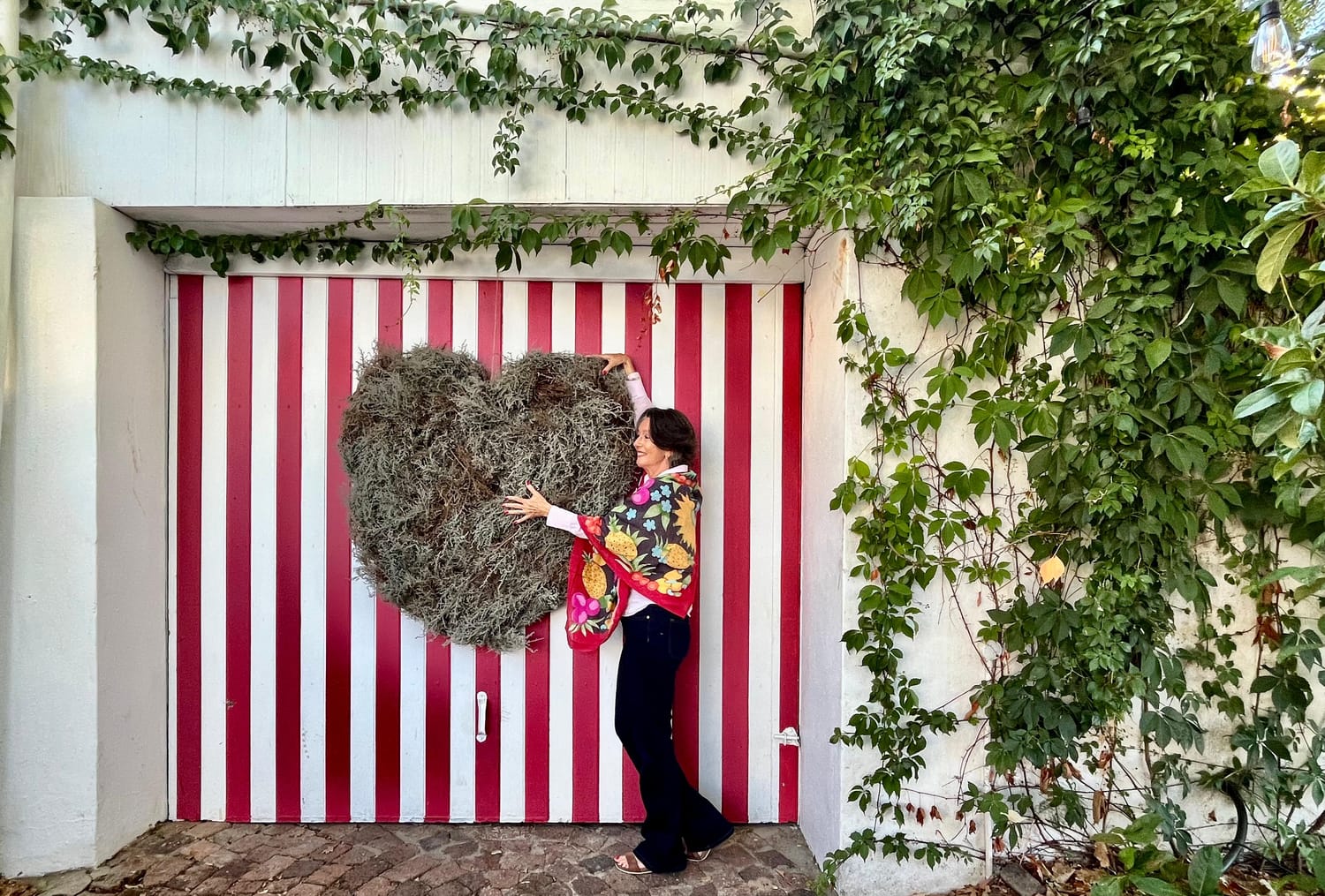 Milandre Vlok standing in front of a dry flower display in a heart shape.