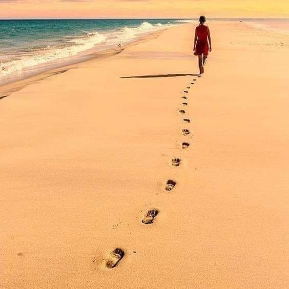 A women walking on the beach leaving footprint behind her