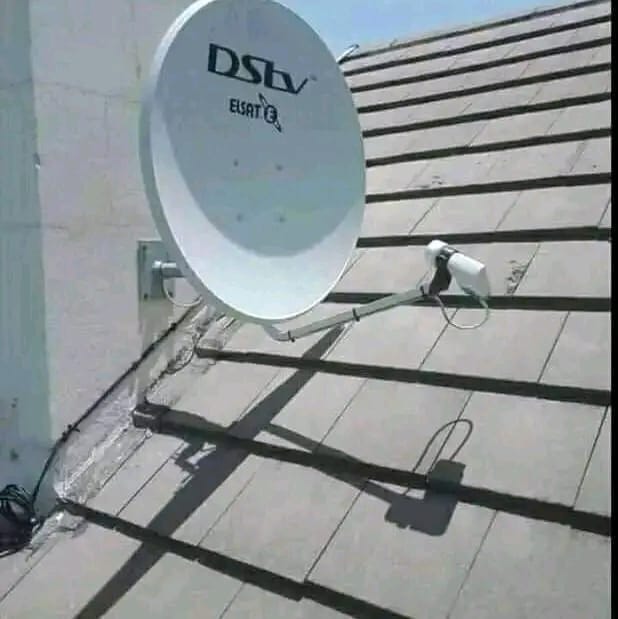 A DStv satellite dish is mounted on a wall and extends over a grey tiled roof, with cables visible.