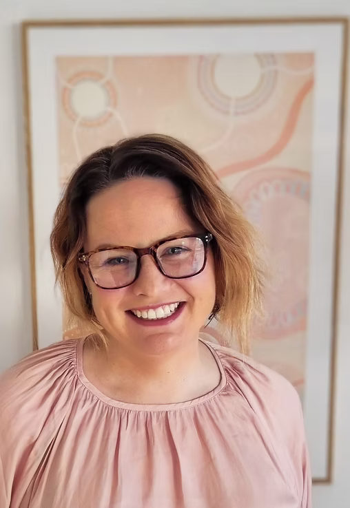 Freya Corboy, Founder of Mumshine Standing in front of an artwork, smiling. 