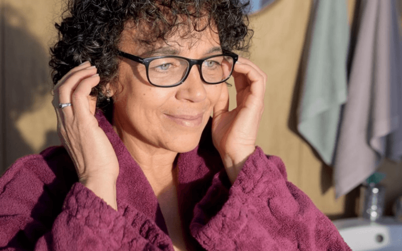 Woman refreshing curly hair in the morning with spray and leave-in cream