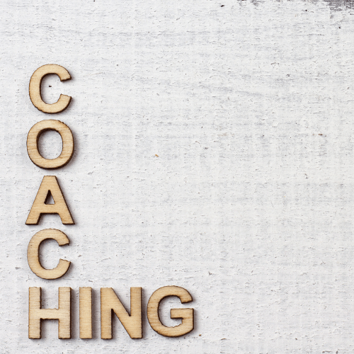 Wooden letters spelling 'COACHING' on a rustic white background, symbolizing coaching and healing containers for personal and professional growth.