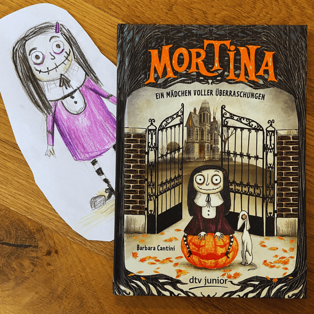 Kinderbuch „Mortina – Ein Mädchen voller Überraschungen“ von Barbara Cantini. Das Buch liegt dekorativ fotografiert auf einem Tisch – perfekte Halloween-Lektüre für Grundschulkinder.