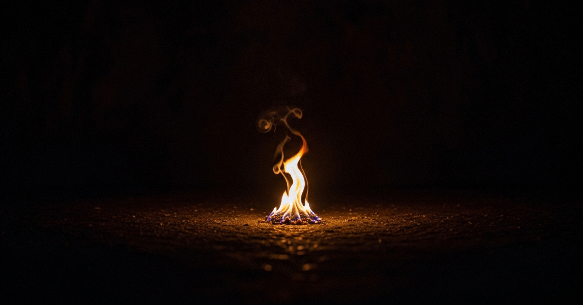 A small flame burns steadily in darkness, symbolizing inner strength, resilience built through hardship, and the quiet power that grows from enduring pain over time.