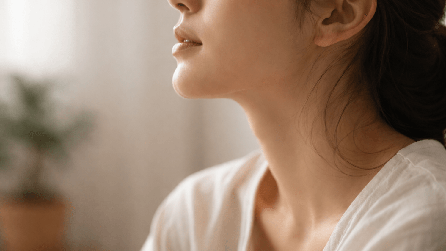 Close-up side view of a person relaxing their jaw in a calm indoor setting with soft natural lighting