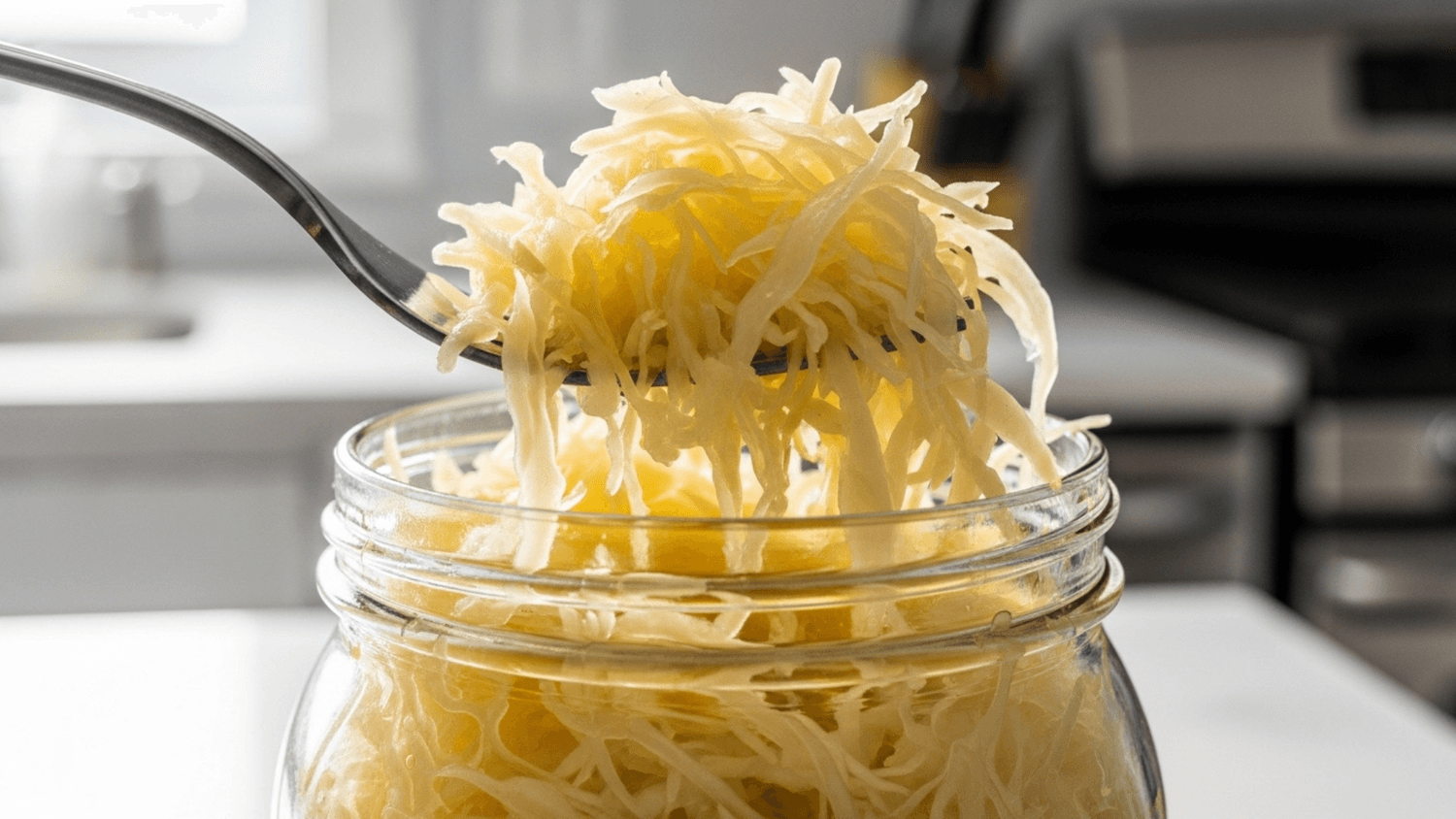 Close-up of sauerkraut in a glass jar with a fork lifting a portion, highlighting texture and freshness