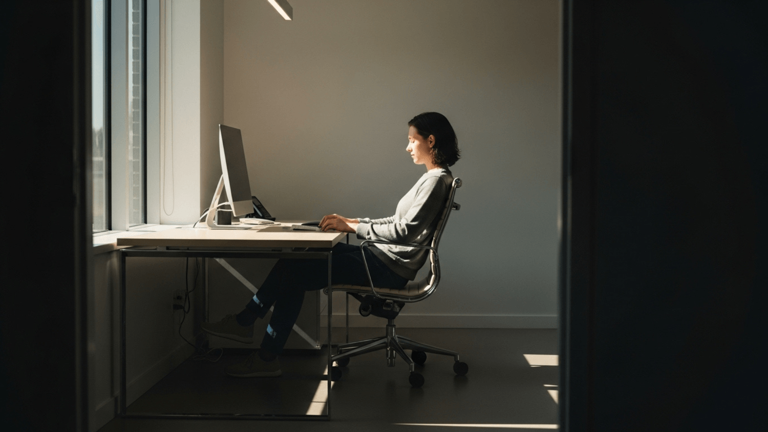 Person sitting calmly at a clean desk during daylight with sunlight filling the room creating a sense of balance and control