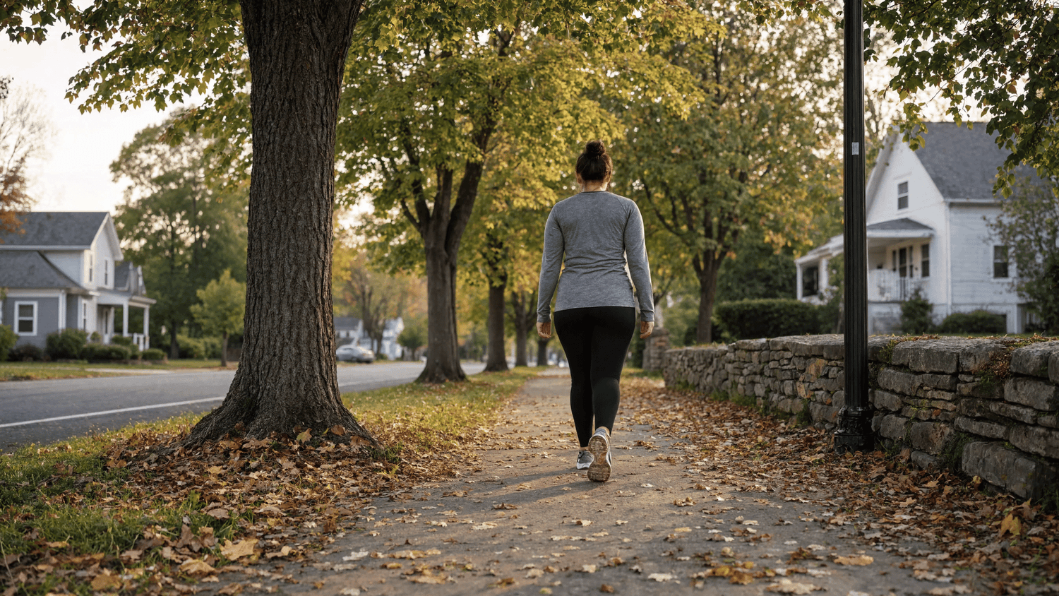 Adult taking a restorative walk along a quiet neighborhood path in the late afternoon.