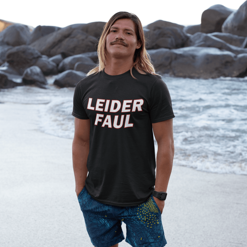 Mann am Strand trägt schwarzes Leider Faul Humor Shirt mit minimalistischer Typografie