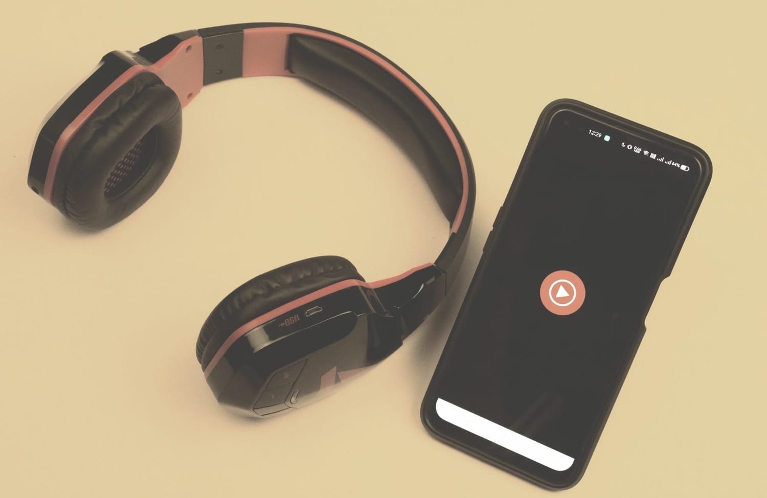Headphones beside a smartphone with play button on screen — symbolizing audio practice for focus and clarity.
