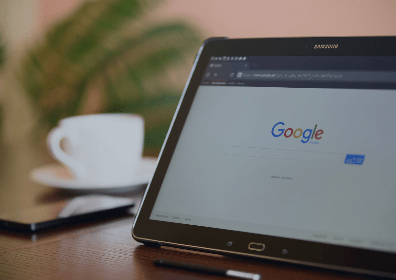 Samsung-nettbrett med Google-søkemotoren på skjermen, plassert på et bord med kaffe i bakgrunnen