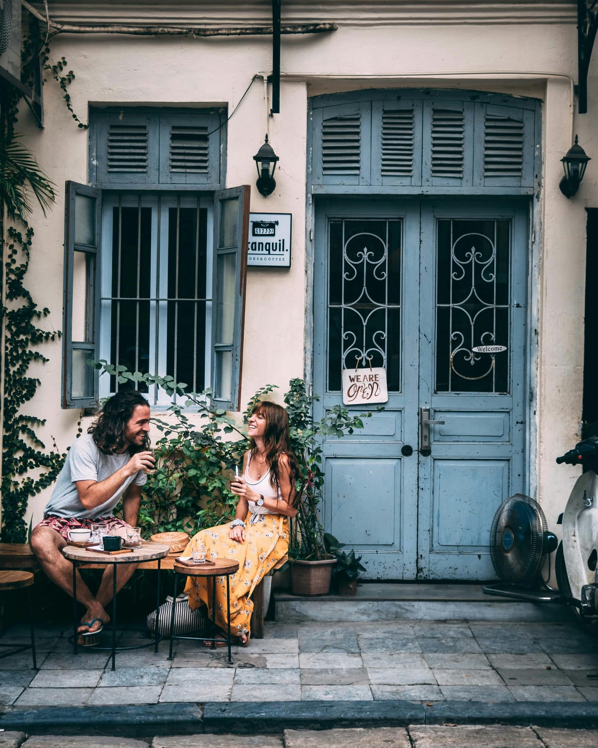 Man and woman sitting outside drinking coffee and laughing