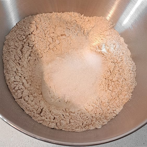 The dry ingredients for the 50/50 bread loaf, white and whole wheat flours, salt, sugar, and instant yeast in the bowl of a stand mixer by ZeinaCooks.com.