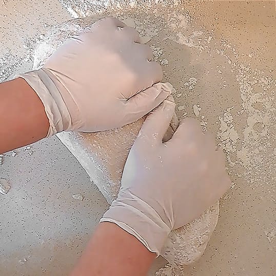 The dough for the 50/50 bread loaf shaped into a loaf and being rolled in flour, by ZeinaCooks.com.
